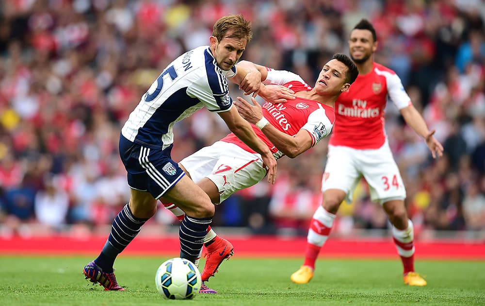 Arsenal's Alexis Sanchez and West Bromwich Albion's Craig Dawson, left, battle for the ball during the English Premier League soccer match at the Emirates Stadium, London.