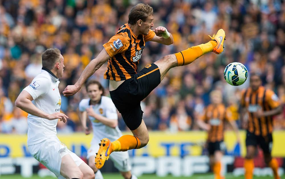 Hull City's Nikica Jelavic, centre, fights for the ball against Manchester United's Phil Jones during the English Premier League soccer match between Hull City and Manchester United at the KC Stadium, Hull, England.