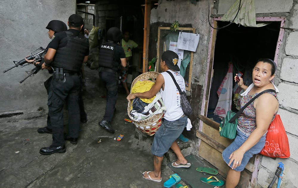 Members of the Philippine National Police conduct a house-to-house search for residents during the demolition of a squatters' community at suburban Caloocan city, north of Manila, Philippines.