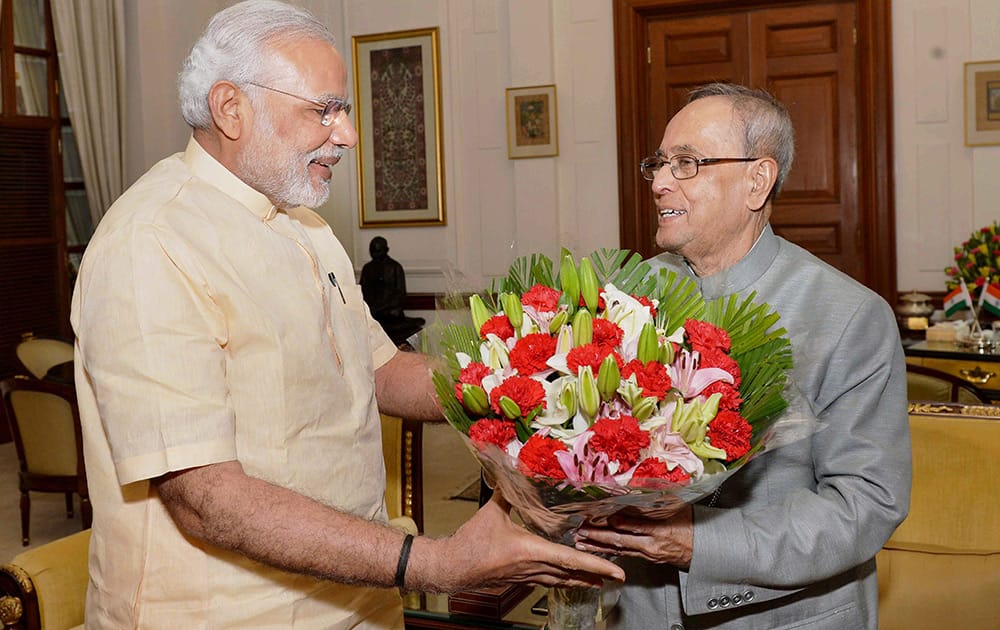 Prime Minister Narendra Modi presents a bouquet to President Pranab Mukherjee at Rashtrapati Bhavan in New Delhi.