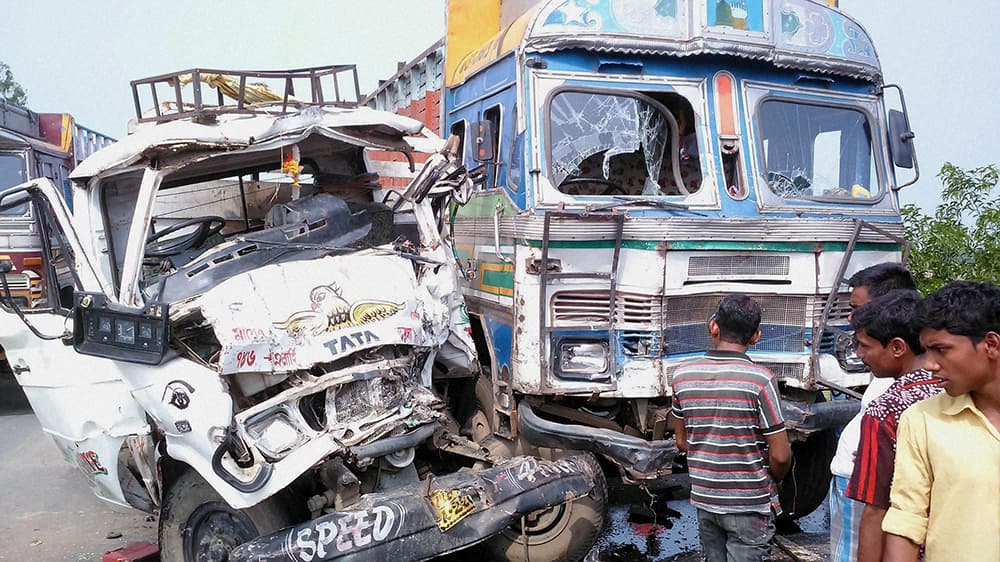 Passers-by looking at the damaged pickup van and truck after an accident at National Highway in South Dinajpur district of West Bengal.