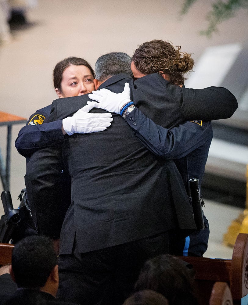 Two Omaha police officers embrace Hector Orozco, the husband of Kerrie Orozco, near the end of her funeral service at St. John's Catholic Church at Creighton University in Omaha, Neb. Orozco, 29, was shot and killed May 20, 2015 in Omaha.