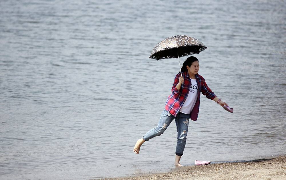 A visitor cools down as she soaks her legs in the water under the scorching sun at Odaiba Seaside Park in Tokyo.