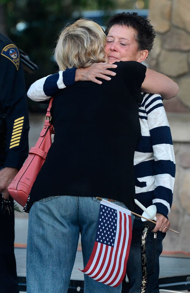 Julie Benner, right, is consoled before a candlelight vigil for her husband, Gregg Benner, a fallen Rio Rancho police officer Gregg Benner, in Rio Rancho, N.M.