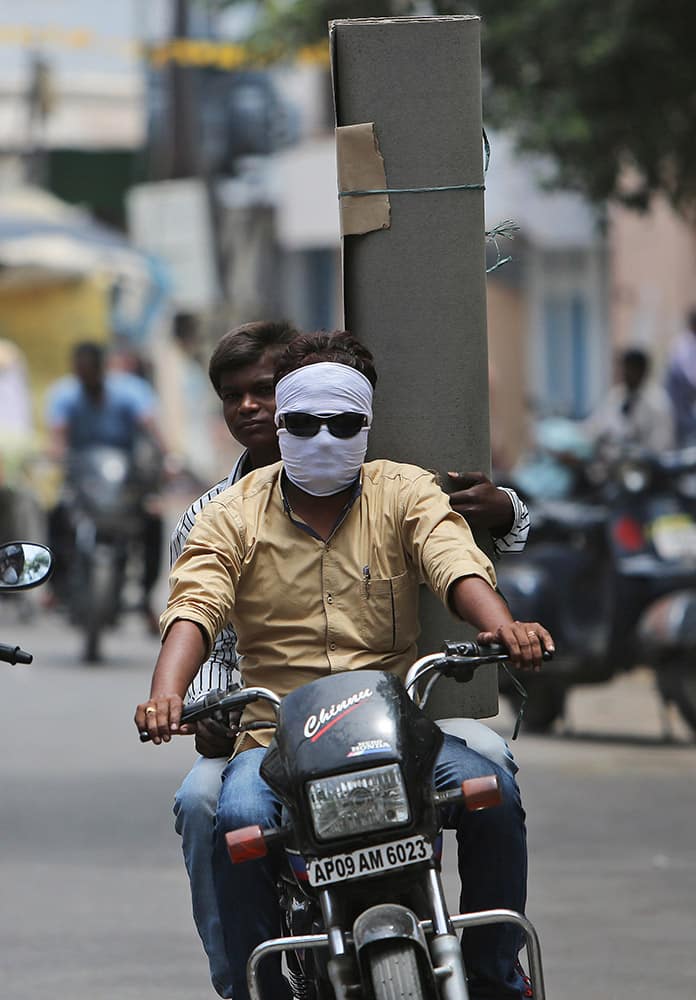 A motorist covers his face with a scarf to protect himself from the heat on a hot summer day in Hyderabad.