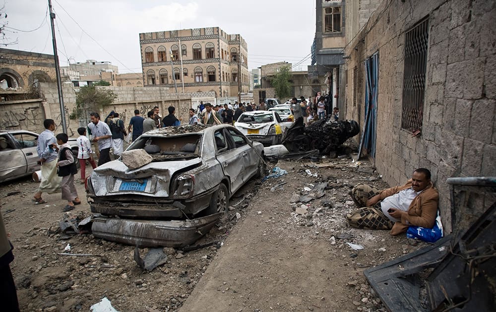 A man rests next to his car destroyed by Saudi-led airstrikes in Sanaa, Yemen.