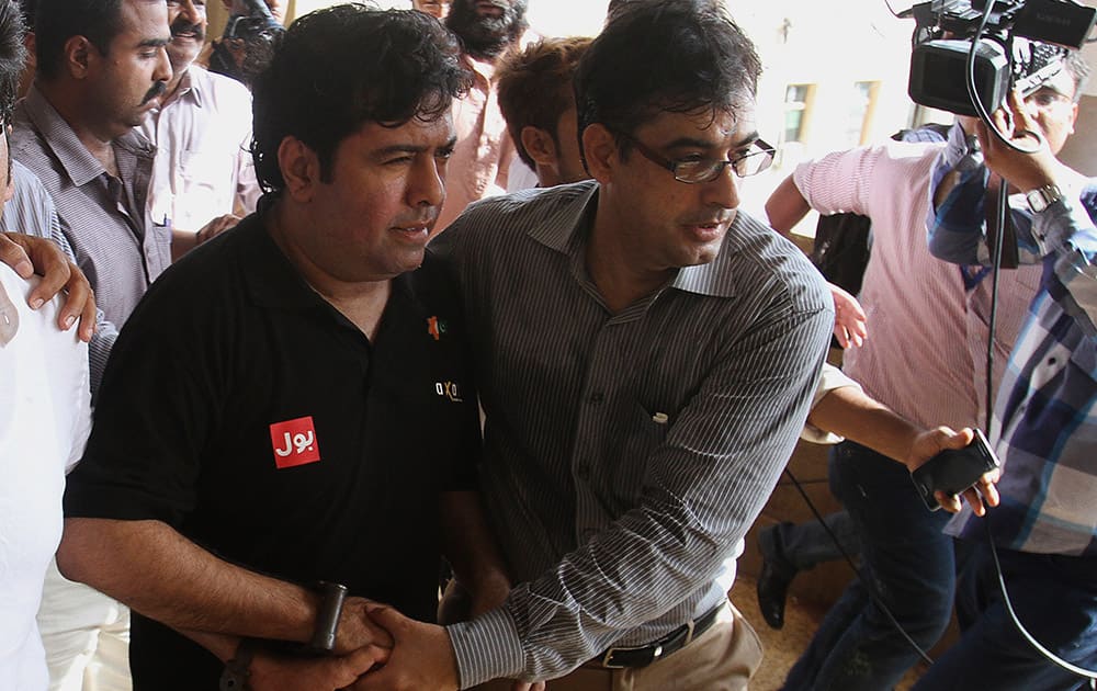 An officer of the Federal Investigation Agency escorts Shoaib Sheikh, the chief executive officer of software company Axact, to a court in Karachi, Pakistan. A Pakistani judge ordered police Wednesday to hold and question the embattled CEO for a week on allegations he oversaw a global diploma mill, as broadcasters aired images of blank degrees stacked in his firm's offices. 