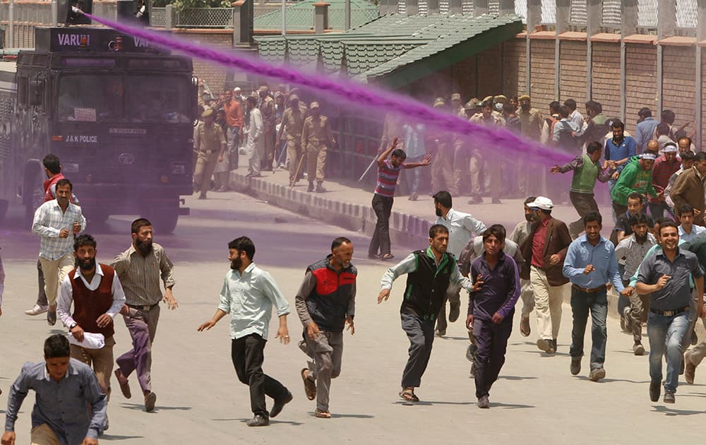 Colored water from water cannons hit Kashmiri government employees during a protest in Srinagar.