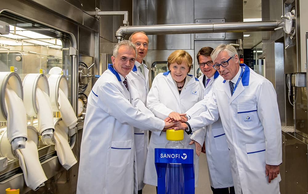 German Chancellor Angela Merkel , Sanofi CEO Oliviere Brandicourt, right, General Manager Martin Siewert, Hesse Interior Minister Boris Rhein, second from right, and Frankfurt's city mayor Peter Feldmann, left, push the button to start a new production facility for insulin during a visit of the Sanofi pharmaceutical company in Frankfurt, Germany.