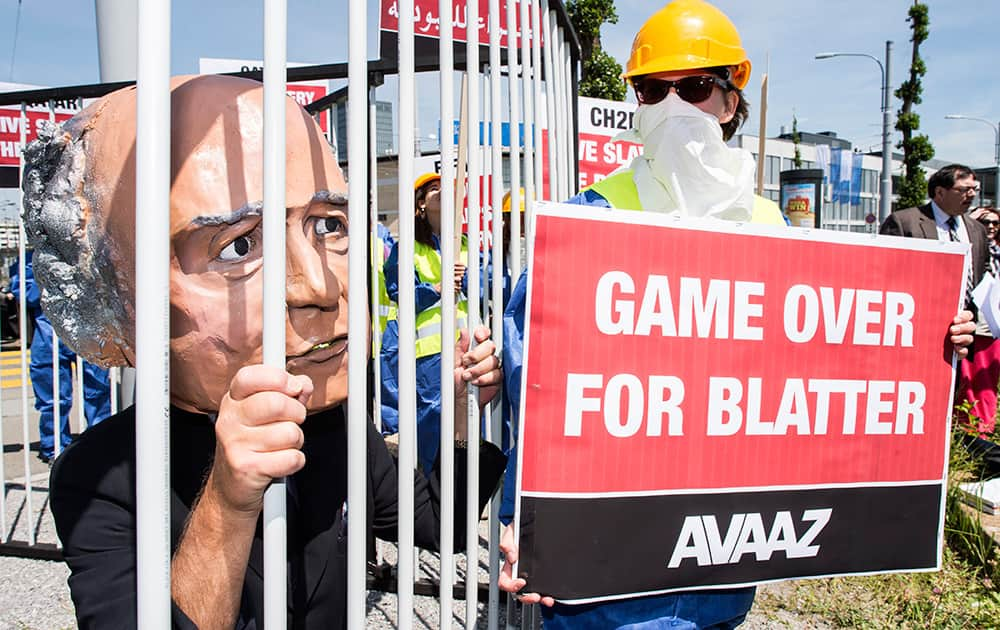 An activist with a giant mask of FIFA President Sepp Blatter stands in a cage as others hold posters during a protest by the Avaaz organization in front of the Hallenstadtion in Zurich, Switzerland.