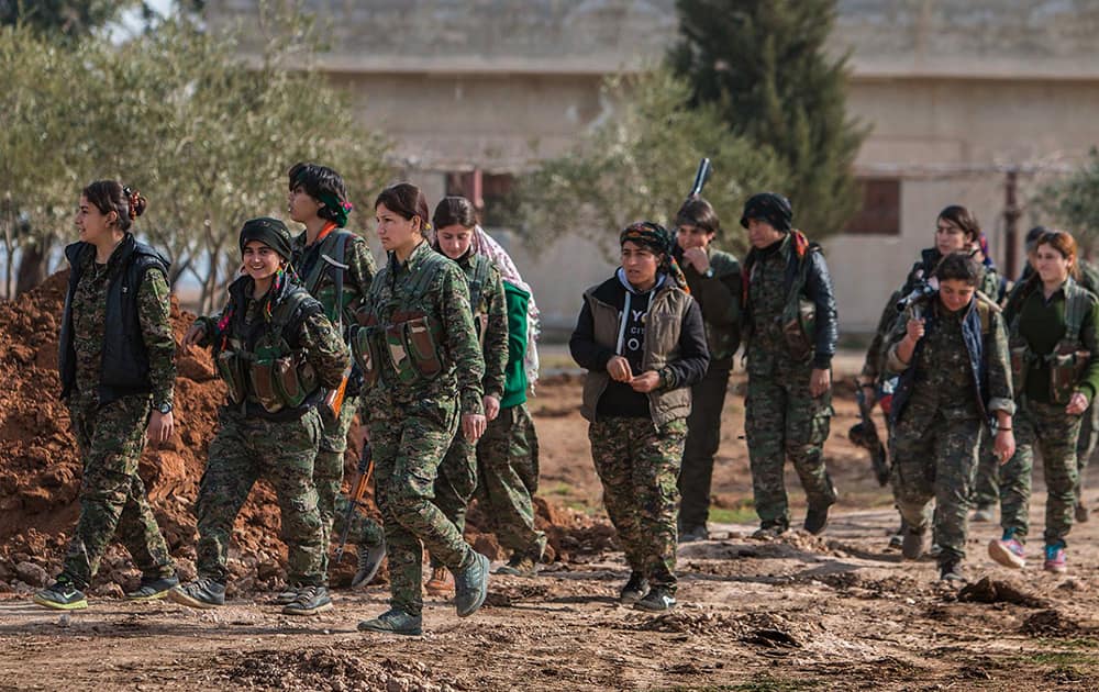 This photo provided by the Kurdish fighters of the People's Protection Units (YPG), which has been authenticated based on its contents and other AP reporting, Kurdish female fighters of the YPG, carry their weapons as they walk in the frontline of Kery Sabee village, northeast Syria. 