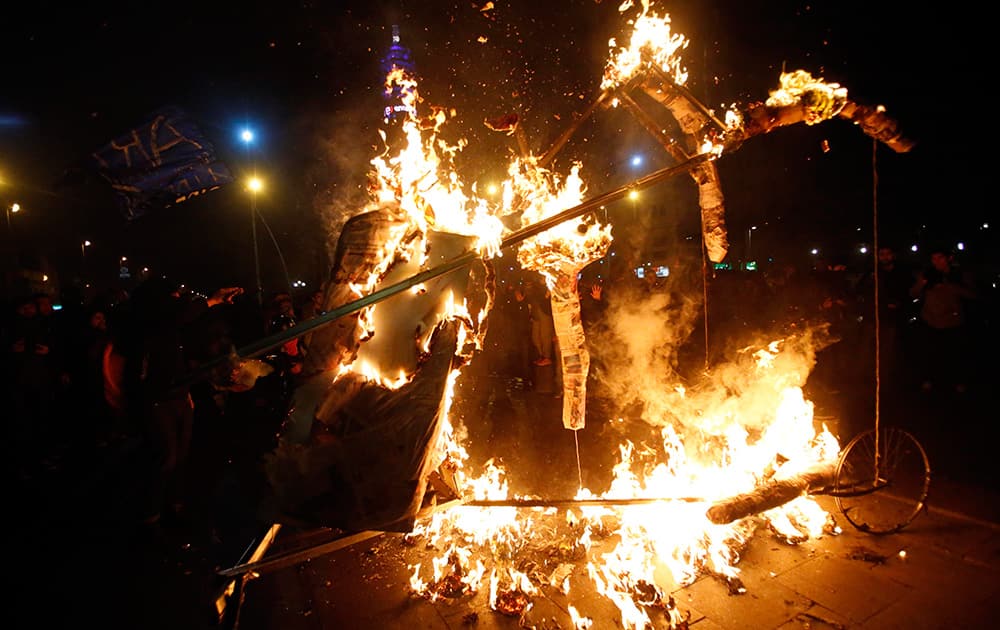 A group of demonstrators burn a paper effigy of a hand representing Chile's president Michelle Bachelet, outside the palace of La Moneda in Santiago, Chile.