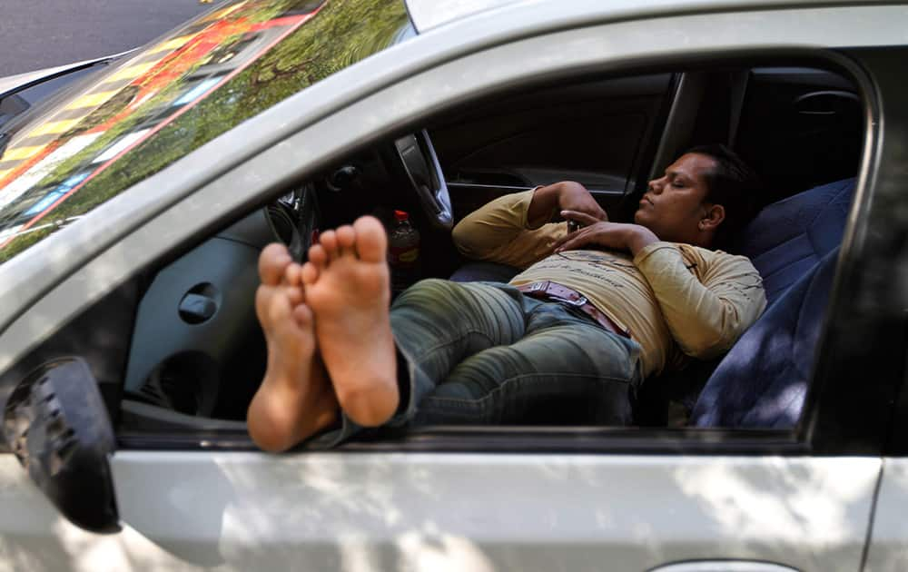 A man takes a nap inside a car on a hot summer day in Ahmadabad.