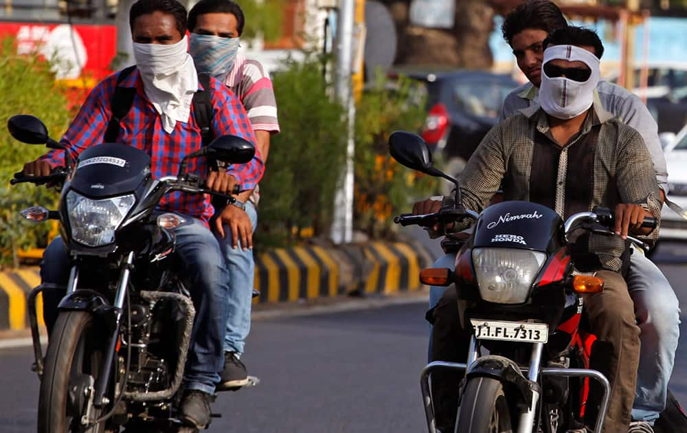 Men covers their face with a scarf to protect themselves from the heat on a hot summer day in Ahmadabad.