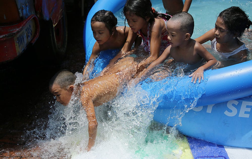 A Filipino boy falls off the side of an inflatable pool in Manila, Philippines as they enjoy the last weekend before school starts in Manila, Philippines .