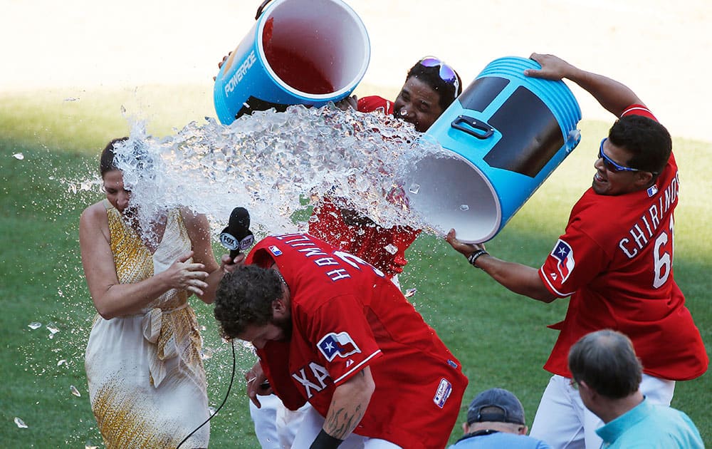 Texas Rangers' Elvis Andrus, background, and Robinson Chirinos, right, douse teammate Josh Hamilton in celebration of his 2 RBI walk-off hit during the ninth inning of a baseball game against the Boston Red Sox, in Arlington, Texas. 