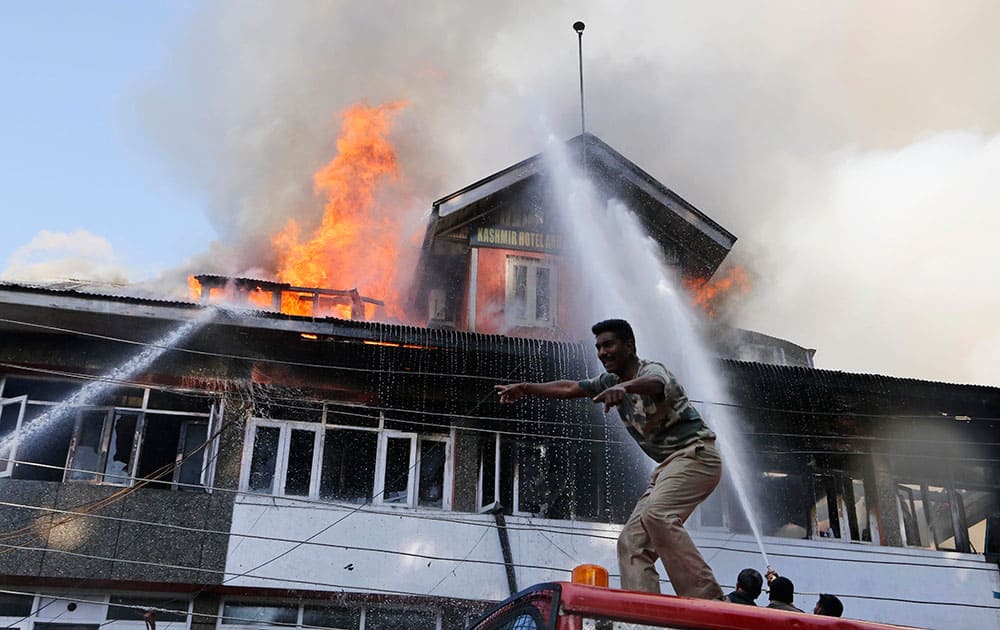 A paramilitary soldier gives directions as he stand on a fire engine, as firefighters work to extinguish a fire in a building in Srinagar.