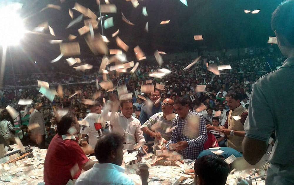 People throw huge Indian rupees during the religious song programme at the inauguration of a temple in Kahambalia village of Jamnagar district.