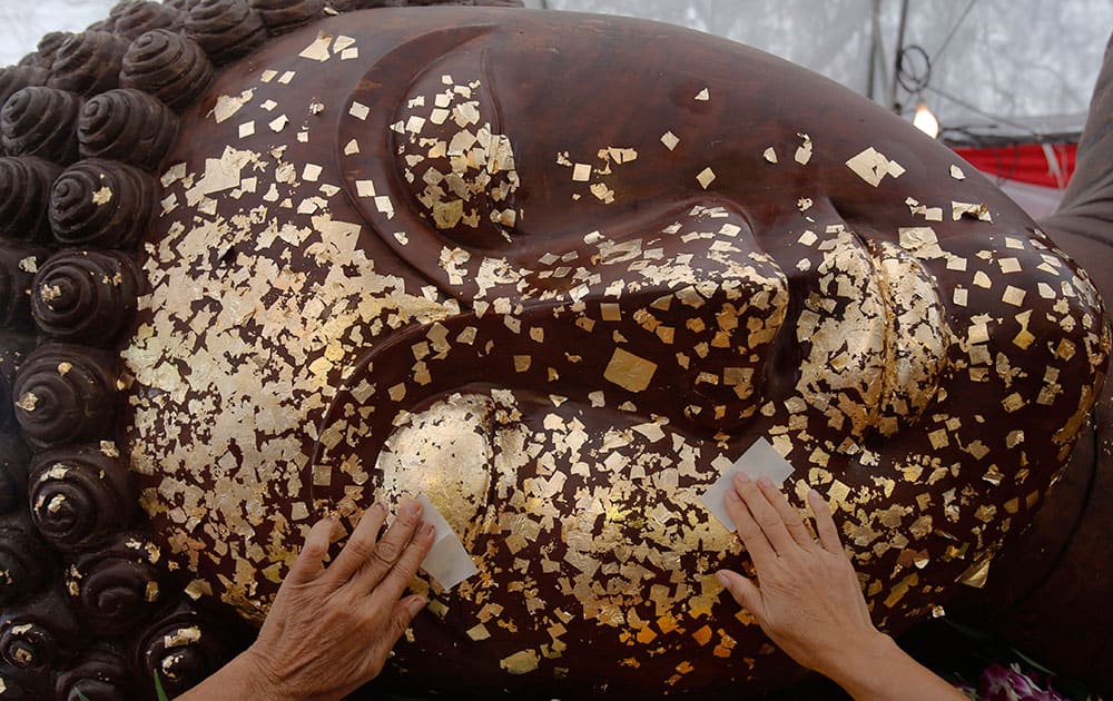 Thai Buddhists put gold leaf on the face of a giant Buddha statue for good luck at Royal Field in Bangkok, Thailand, as part of Wesaka Bucha activities. 