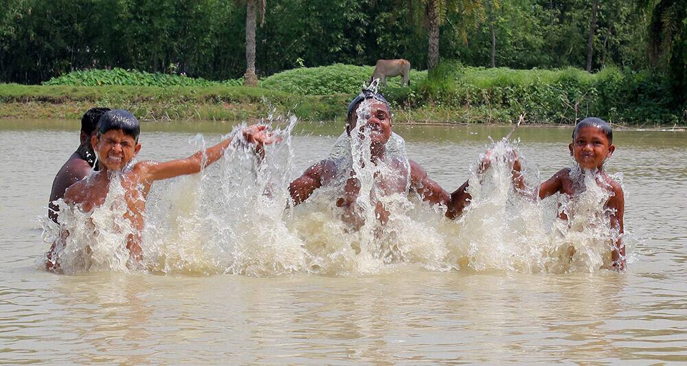 Children play in water during hot summer at a village in South Dinajpur district of West Bengal.