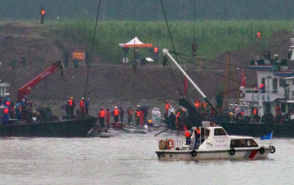 A marine boat patrols past as rescuers work on the capsized ship, center, on the Yangtze River in Jianli county of southern China’s Hubei province, as seen from across the river from Huarong county of southern China’s Hunan province.