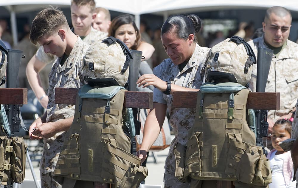 A Marine chokes back tears as she reaches out to touch the helmet of one of the six Marines killed in a helicopter crash while helping with disaster relief in earthquake-devastated Nepal, during a memorial service at Camp Pendleton, Calif.