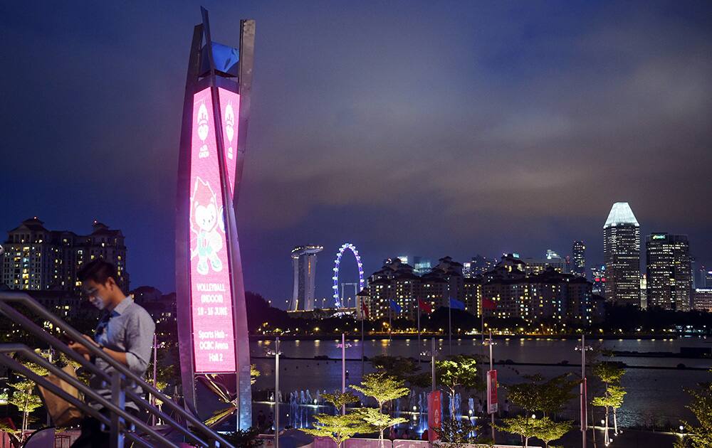 The unlit torch for the 2015 South East Asian Games in Singapore is photographed with the Singapore skyline in the distance.