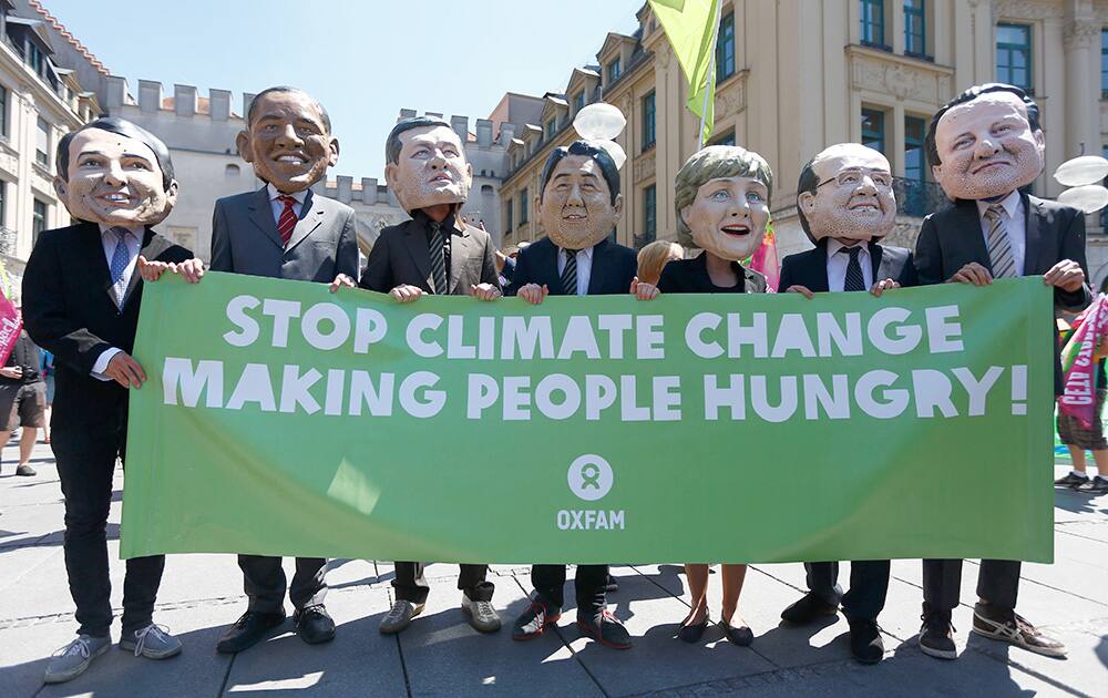 Demonstrators with masks depicting, Italian Prime Minister Matteo Renzi, US President Barack Obama, Canadian Prime Minister Stephen Harper, Japanese Prime Minister Shinzo Abe, German Chancellor Angela Merkel, French President Francois Hollande and British Prime Minister David Cameron hold a poster warning of climate change during a protest against the upcoming G-7 summit in Munich, southern Germany.