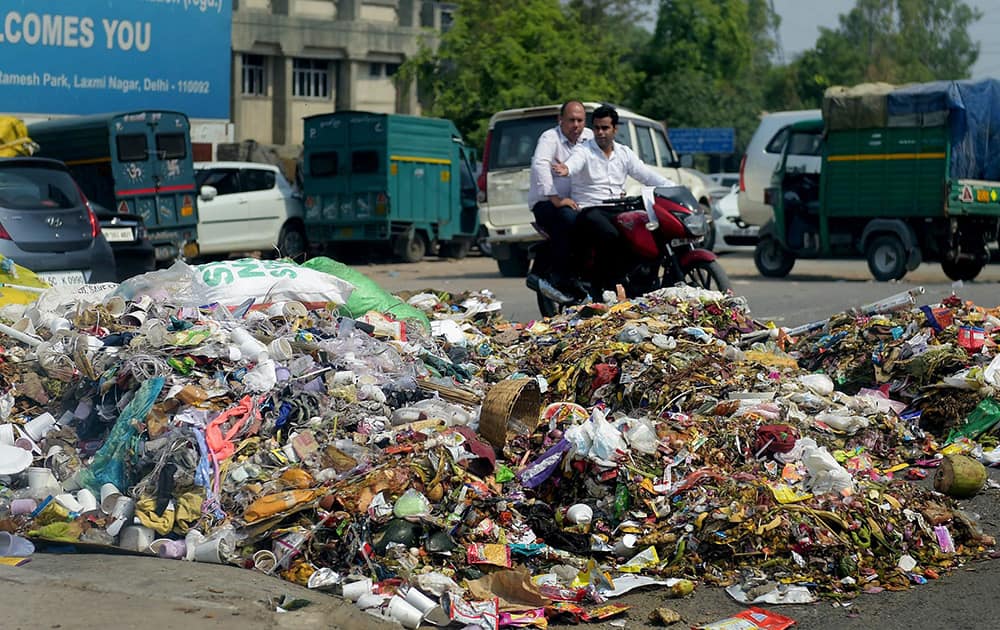 People looking at garbage dumped on a road at Laxmi Nagar on the eve of World Environment day in New Delhi.