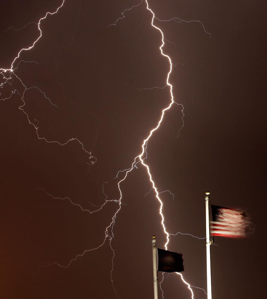 Lightning strikes behind flags at the Kansas Veterans' Cemetery, in WaKenney, Kan. 