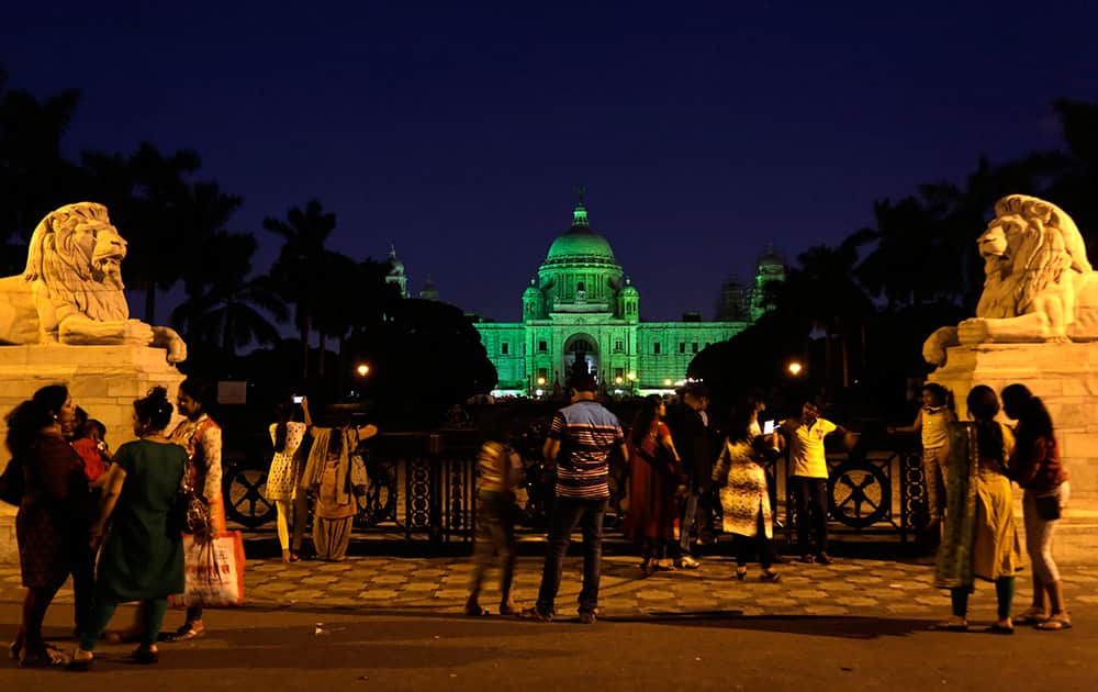 Tourists gather in front of Victoria Memorial Hall, a city icon, as it is illuminated with green light to spread awareness on the need for a greener environment on the eve of World Environment Day in Kolkata.