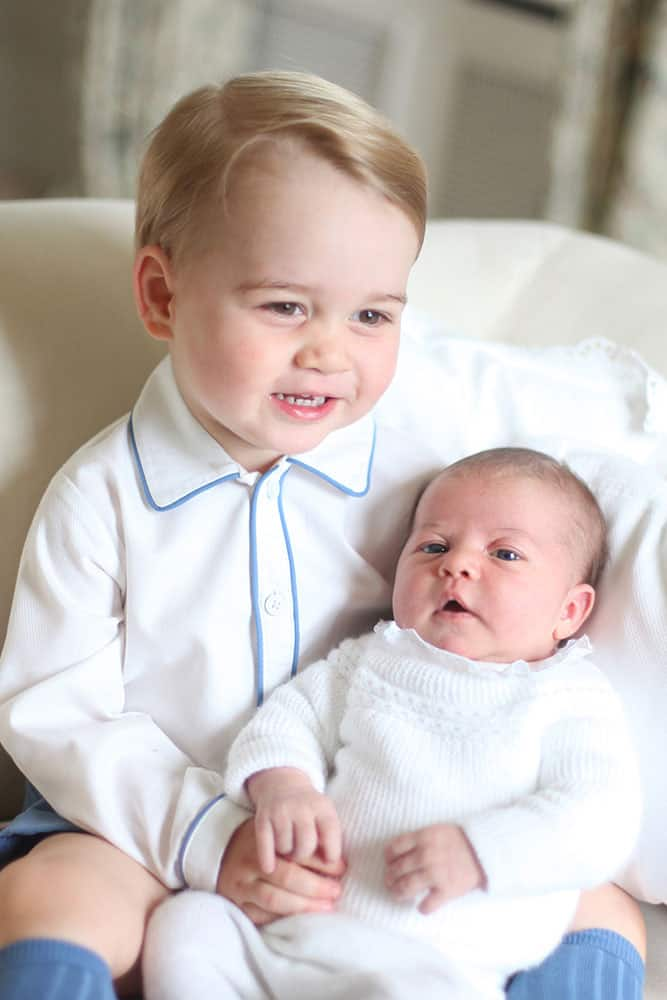 his image made available by Kensington Palace Saturday, June 6, 2015, taken by Kate, Duchess of Cambridge, at Anmer Hall, eastern England in mid-May 2015 shows Britain's Princess Charlotte, right, being held by her brother, 2-year-old, Prince George. 