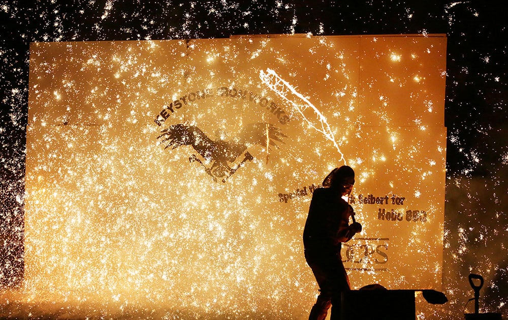 Vaughn Randall of Ithaca, N.Y., slings about 10 pounds of molten iron onto a wall to create a firework like effect during Arts on Fire Festival at the Scranton Historic Iron Furnaces in Scranton, Pa. 