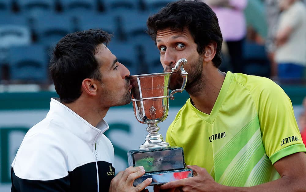 Croatia's Ivan Dodig, left, and Brazil's Marcelo Melo bite the cup after defeating Bob and Mike Bryan of the U.S. in their men's doubles final match of the French Open tennis tournament at the Roland Garros stadium.