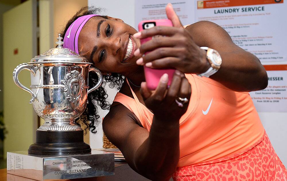 Serena Williams of the U.S. poses for a selfie with the trophy in the cloakroom after winning the French Open Tennis tournament against Lucie Safarova of the Czech Republic, at the Roland Garros stadium.