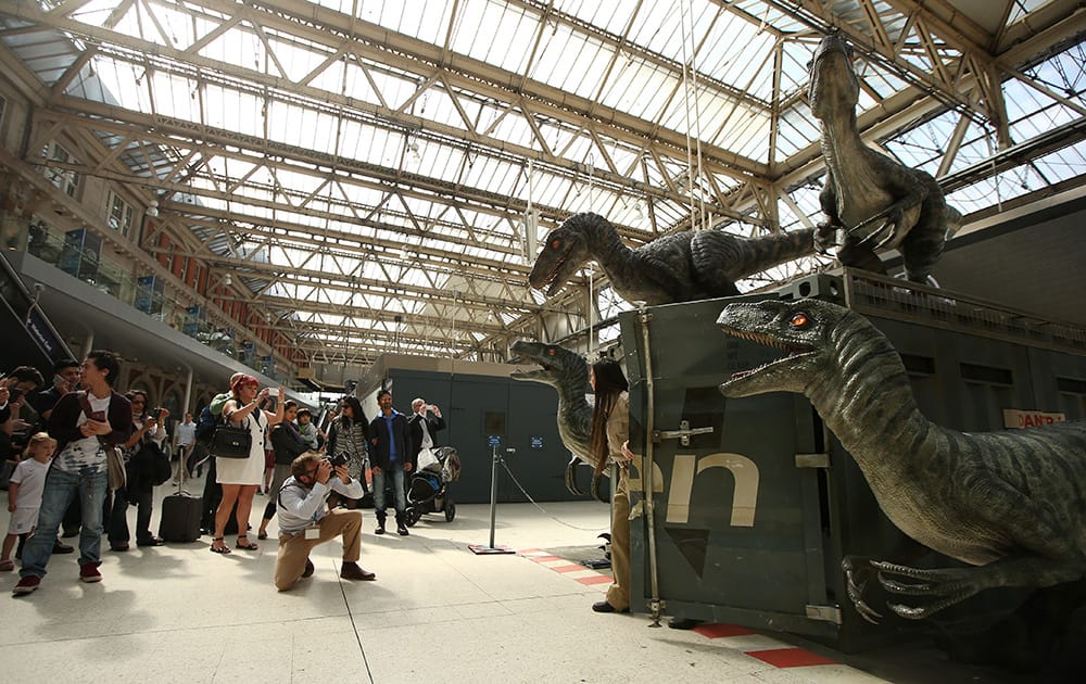 Commuters at Waterloo station stop to take photographs of the model Raptors as part of the Jurassic World Waterloo exhibition in central London.