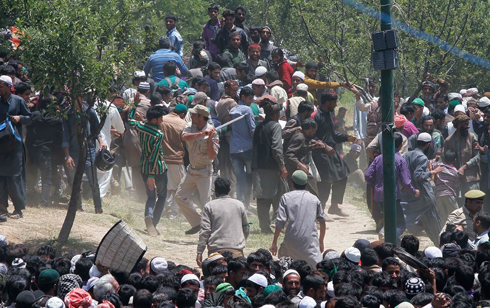 A policeman uses a baton to control the crowd during a free rice distribution as nomadic Kashmiri Muslims gather at the forest shrine of Miyan Peer, in Baba Nagri, about 44 kilometers (28 miles) northeast of Srinagar.