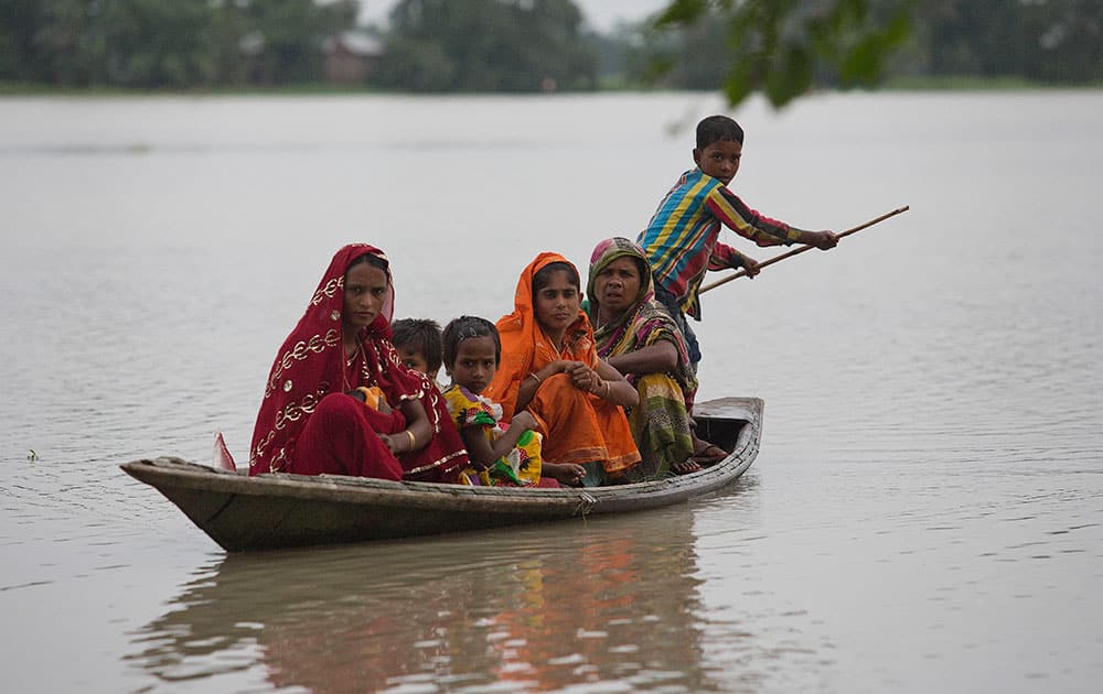 A boy rows a boat as flood effected women and children travel on a boat in Bamuna village about 120 kilometers (75 miles) west of Gauhati, India.