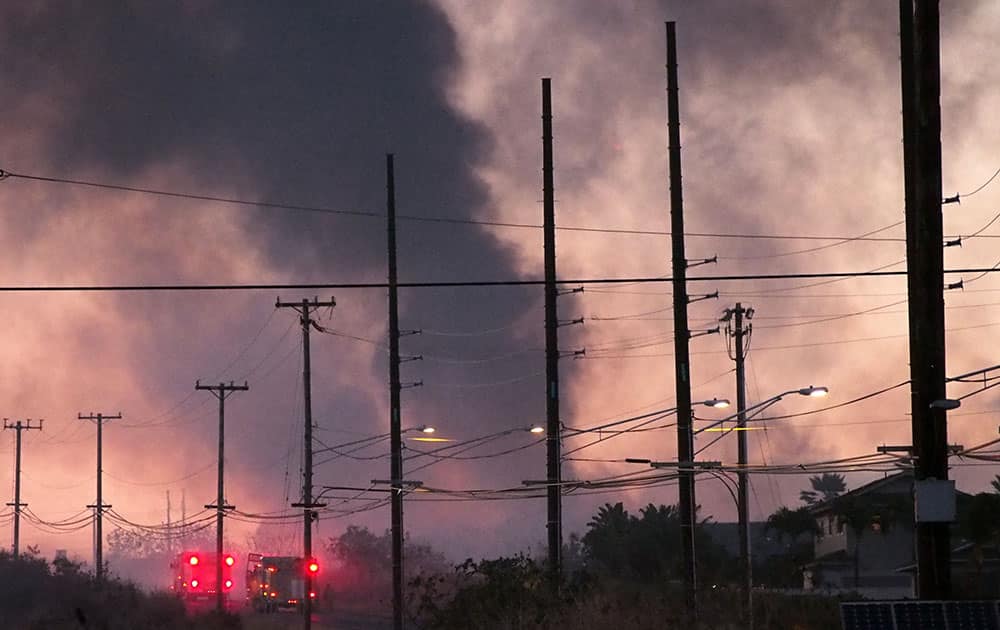 smoke rises from a brush fire in the Kunia neighborhood of Waipahu, Hawaii. Firefighters have contained a west Oahu brush fire that burned more than 200 acres and prompted voluntary evacuations.