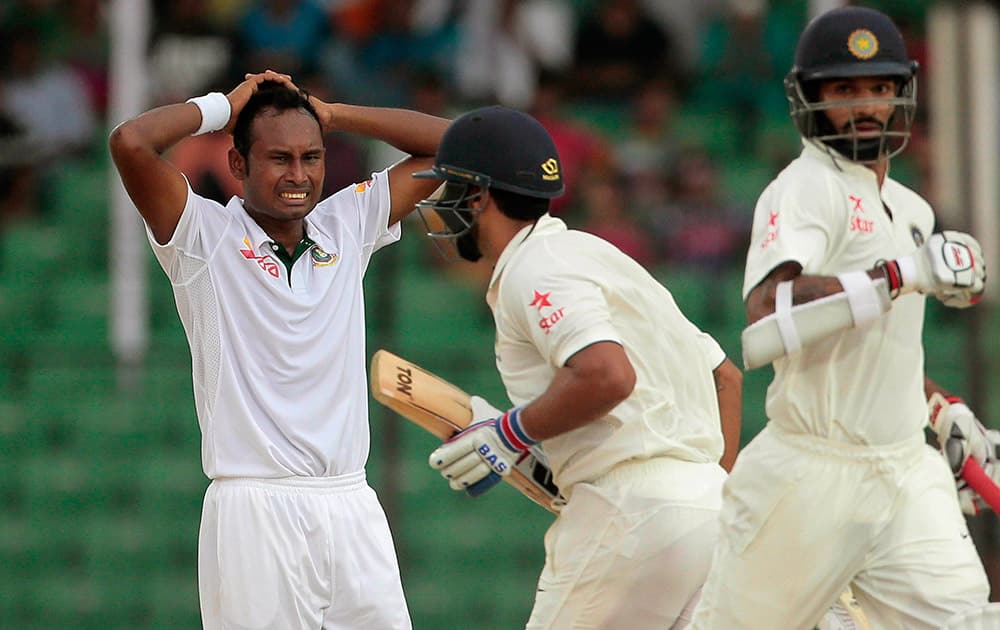 Bangladesh’s Mohammad Shahid, left, reacts as India’s Murali Vijay, center, and Shikhar Dhawan run between wickets during the test cricket match between them in Fatullah, Bangladesh.