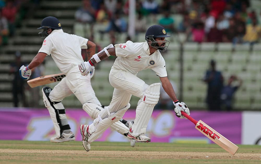 Murali Vijay and Shikhar Dhawan run between wickets during the first day of their test cricket match against Bangladesh in Fatullah, Bangladesh.