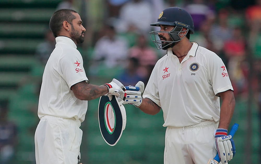 Shikhar Dhawan, celebrates with his teammate Murali Vijay after scoring hundred runs during the first day of their test cricket match against Bangladesh in Fatullah, Bangladesh.