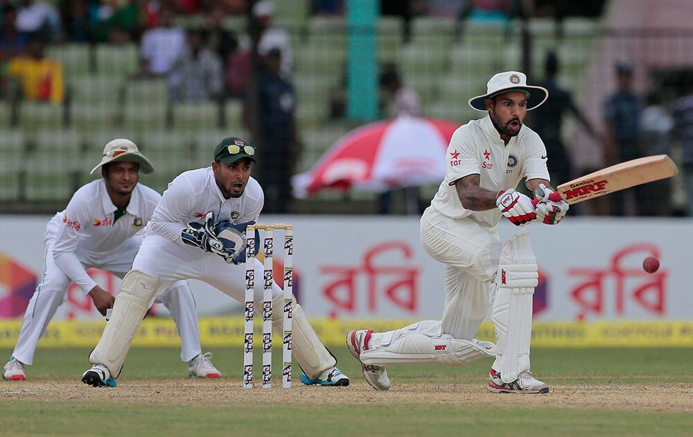 Shikhar Dhawan, plays a shot as Bangladesh’s wicketkeeper Litton Das, center, and Shakib Al Hasan watch during the first day of their test cricket match against Bangladesh in Fatullah, Bangladesh.