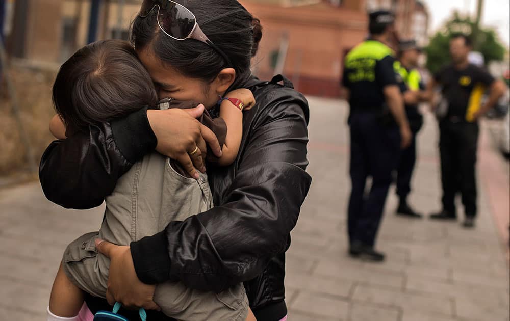 Police and a locksmith talk as Karen Minan, 25 years old, second left, hugs her son Aaron, one and a half year old, after she was evicted in Madrid, Spain.