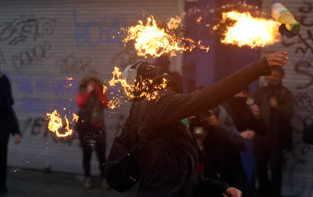 A protester throws a petrol bomb towards the police during a march, demanding more participation in the education reform discussions, in Santiago, Chile.