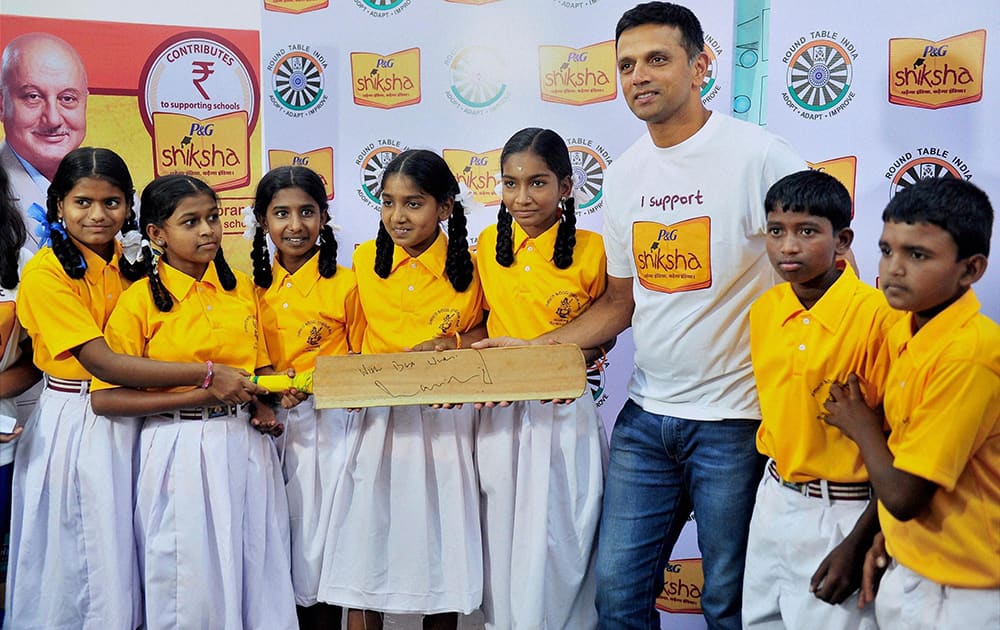 Former Cricketer & U-19 Cricket team Coach Rahul Dravid hands over an autographed cricket bat to the students of a Government Higher Primary school during an event in Bengaluru.