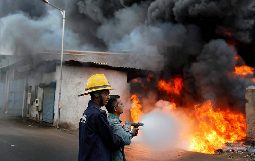 Firefighters extinguishing fire in a market selling used oil barrels in Ahmedabad.