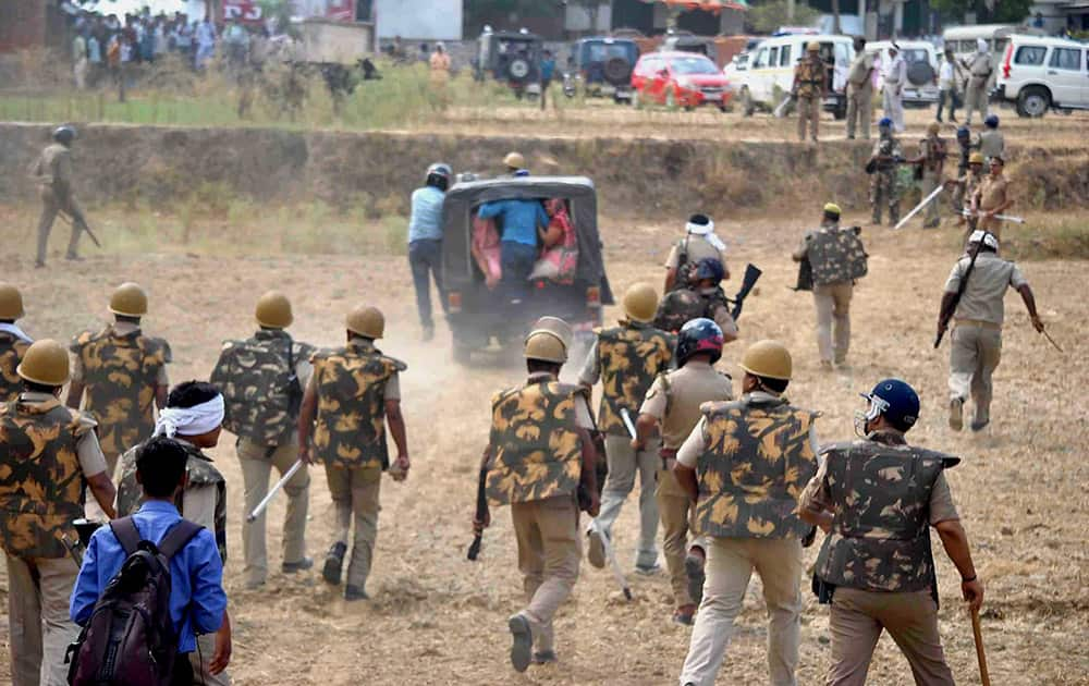 Policemen in action after angry villagers set ablaze houses during the clash at Ghoorpur, in Allahabad.