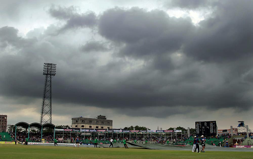 Bangladesh’s ground staff pull covers on the field due to rain during the third day of their test cricket match between Bangladesh and India in Fatullah, Bangladesh.