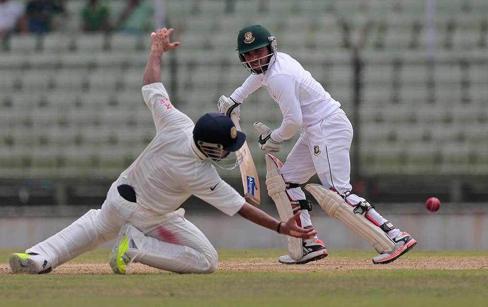 Bangladesh’s Mominul Haque, right, plays a shot, as India's Ajinkya Rahane drives to catch the ball during the fourth day of their test cricket match against India in Fatullah, Bangladesh.